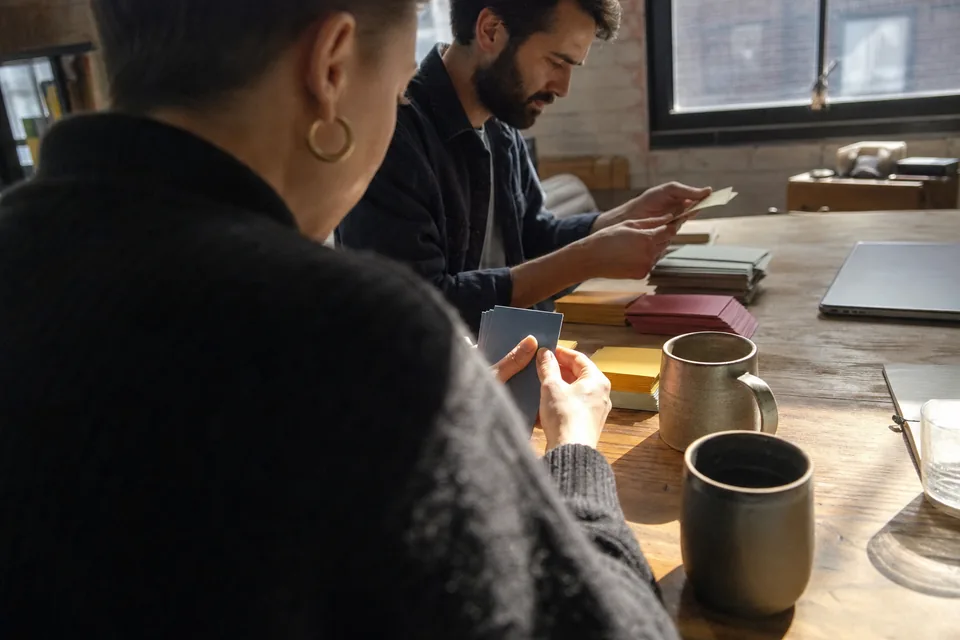 Two colleagues sorting index cards into topic piles on a wooden table