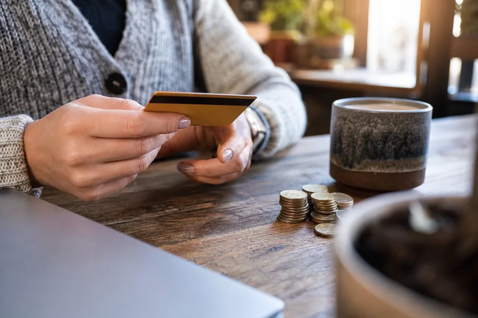 Hands holding a credit card over a desk while deciding on a software subscription
