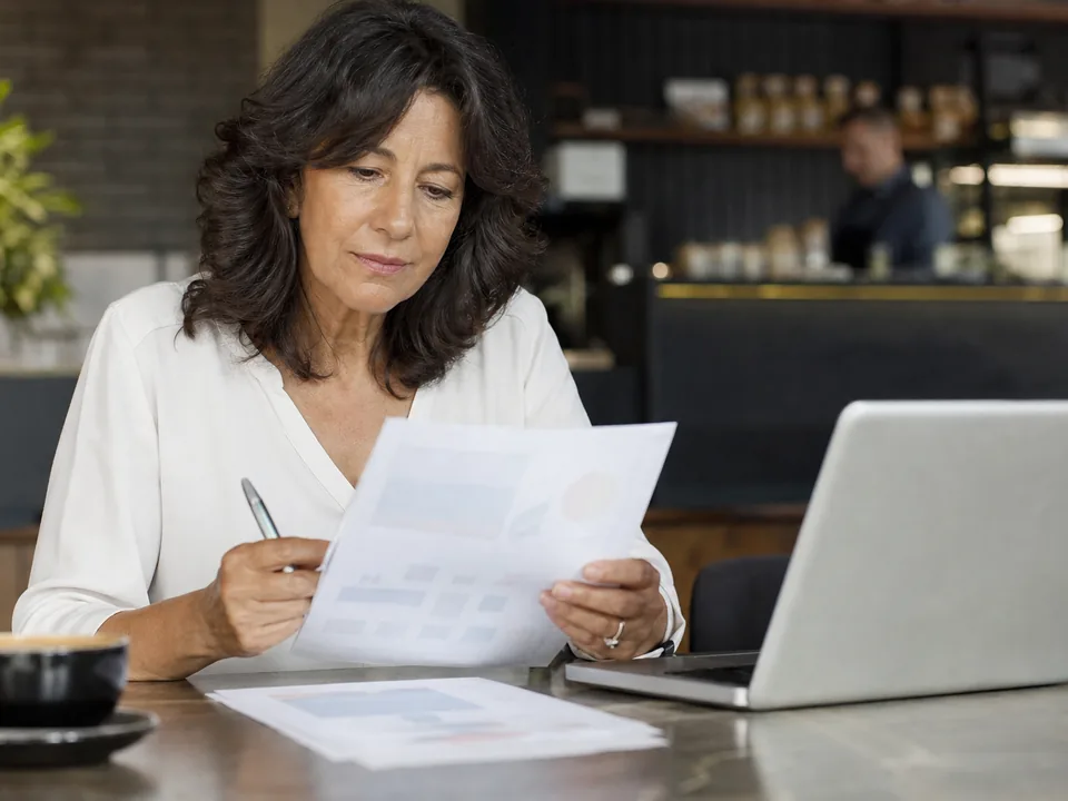 Business owner reviewing a monthly software budget printout with a pen